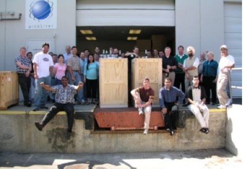 Labcyte team on a loading dock celebrating shipment milestone as first Echo 550 acoustic liquid handling systems ship in wooden crates.