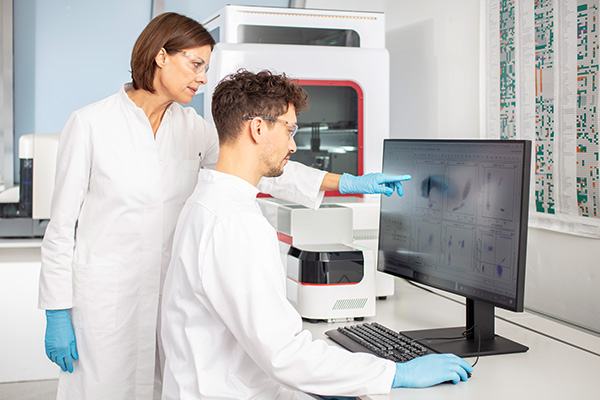 Results of flow cytometry analysis discussed by lab personnel, while CellMek SPS does the sample preparation in the background.