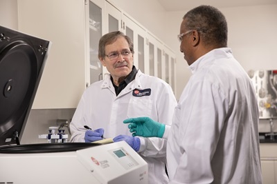 A factory-trained service technician inspecting and performing preventative maintenance on Allegra V-15R benchtop centrifuge with the lab manager observing.
