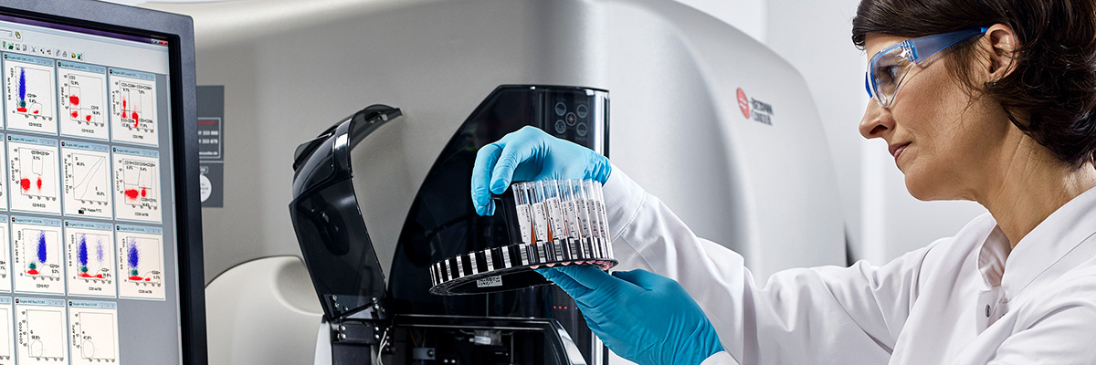 A woman loading a rack of tubes on Navios EX flow cytometer