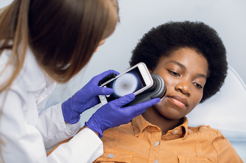 Close up of hands of female doctor holding dermatoscope for study