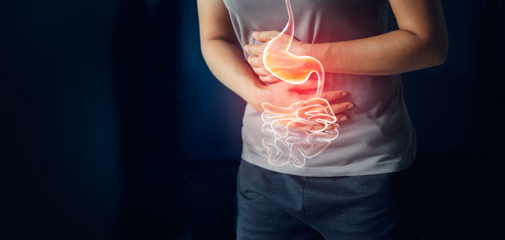 A woman holding her stomach in pain due to a gastrointestinal disease or disorder